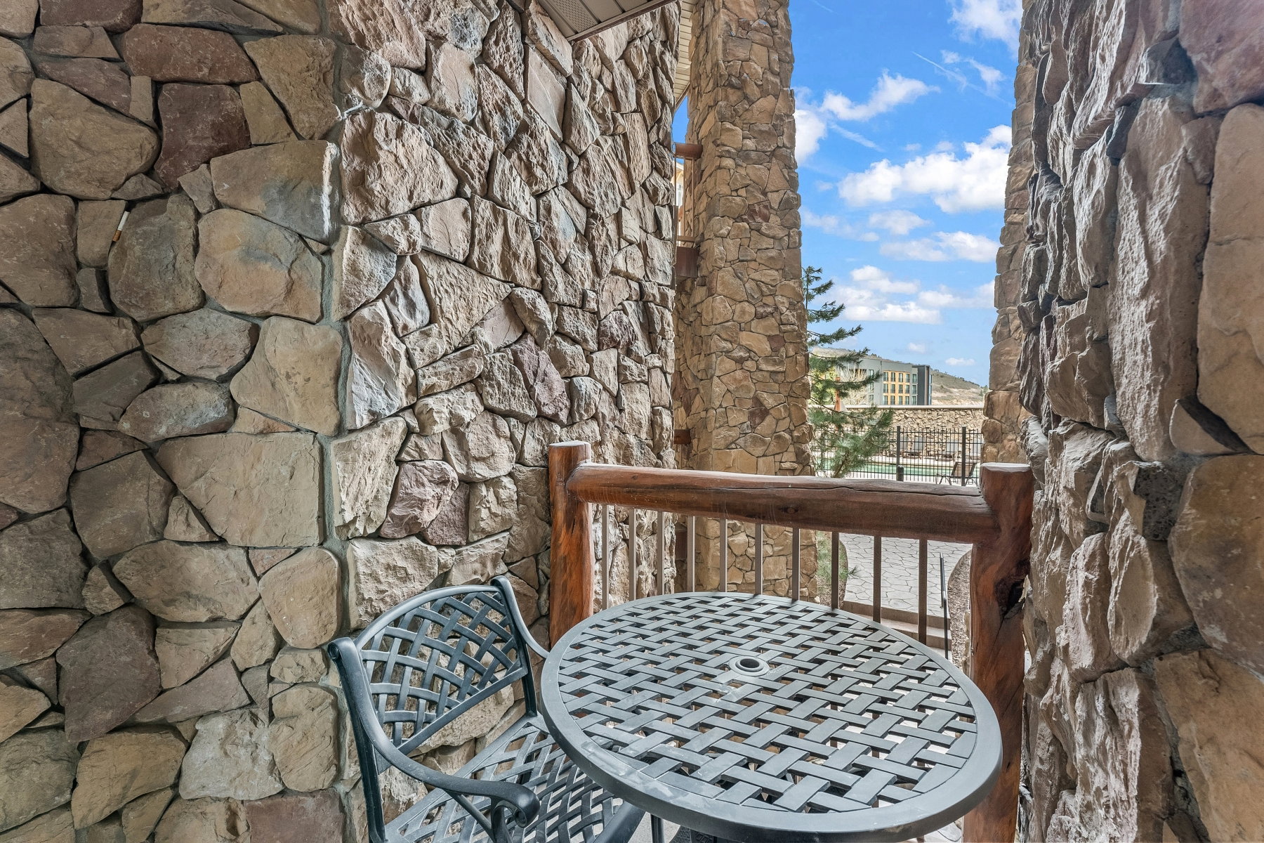 Stone-clad exterior walls featuring a rustic wood railing balcony