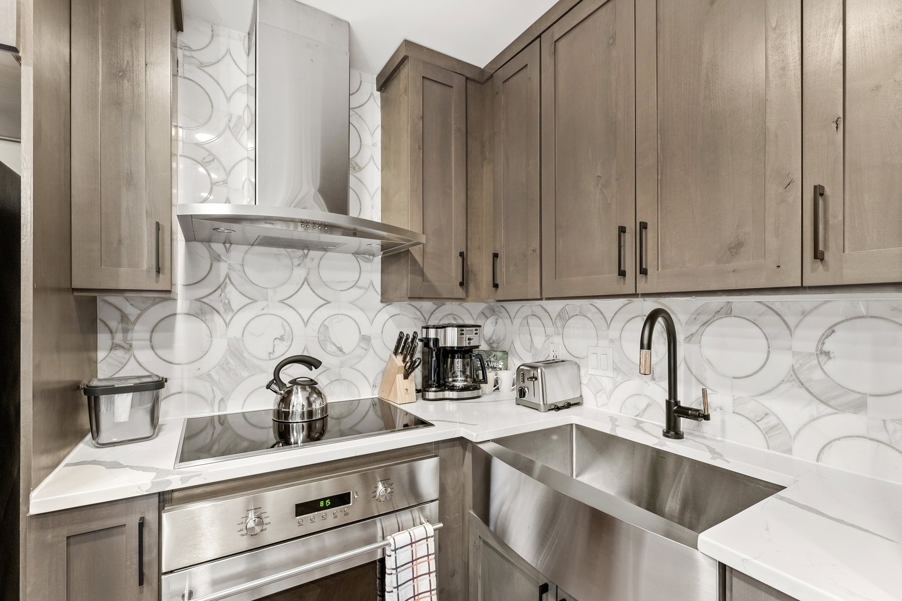Kitchen showcasing a farmhouse-style stainless steel sink, a stainless steel oven with a cooktop, and a matching stainless steel range hood