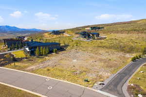 Expansive undeveloped lot featuring natural terrain, a paved road frontage, and distant mountain scenery