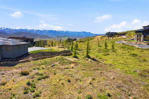 Expansive hillside property featuring distant snow-capped mountain scenery, a gravel driveway, and a retaining wall with stone steps