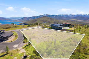Expansive undeveloped lot with a mountainous backdrop, featuring a lake in the distance