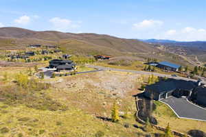 Expansive residential lot featuring a gently sloping terrain, framed by distant mountains and a clear sky