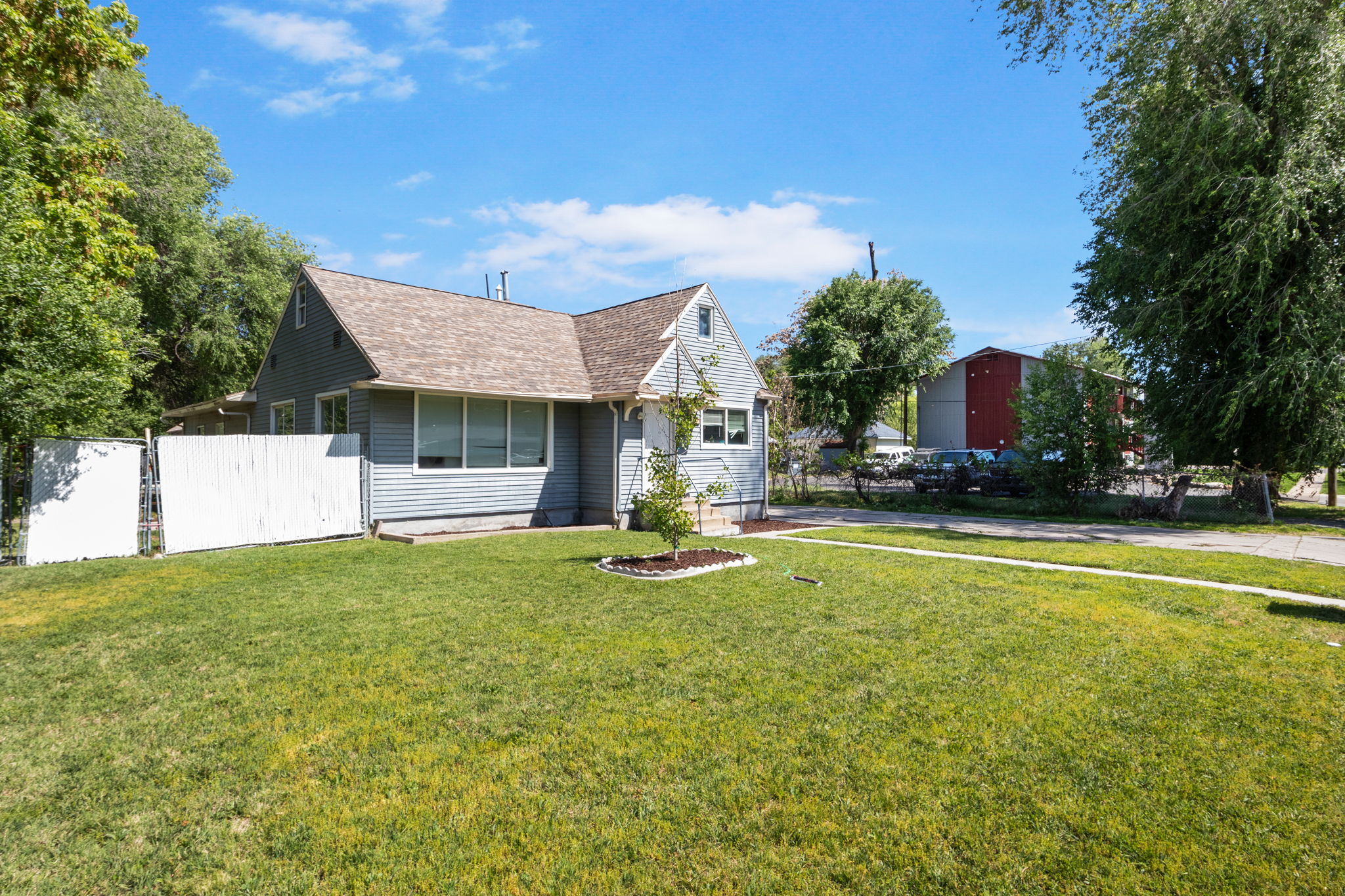 Exterior featuring light blue siding, a brown shingle roof, and multiple windows