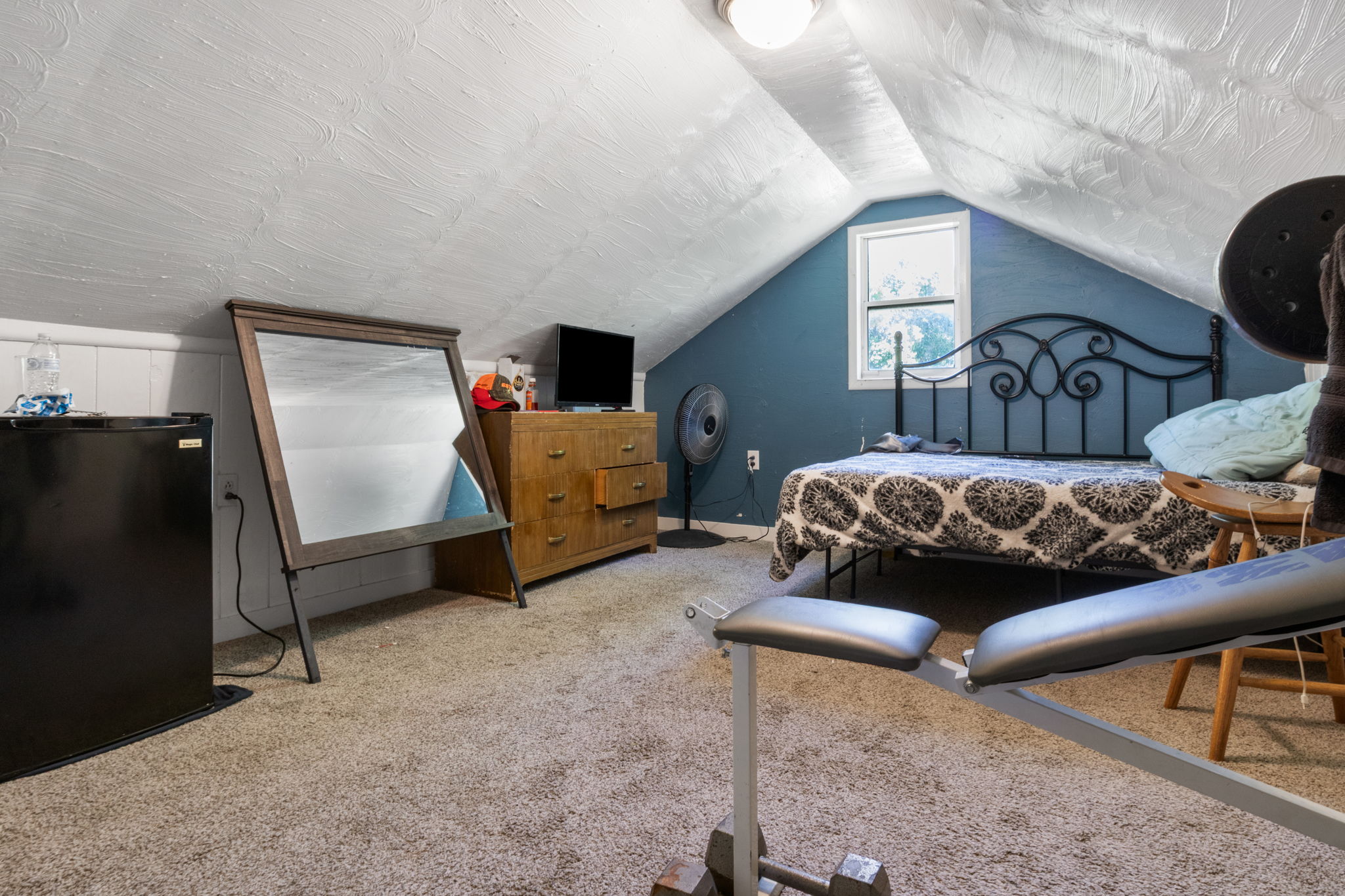 Carpeted room with sloped ceilings and a single window