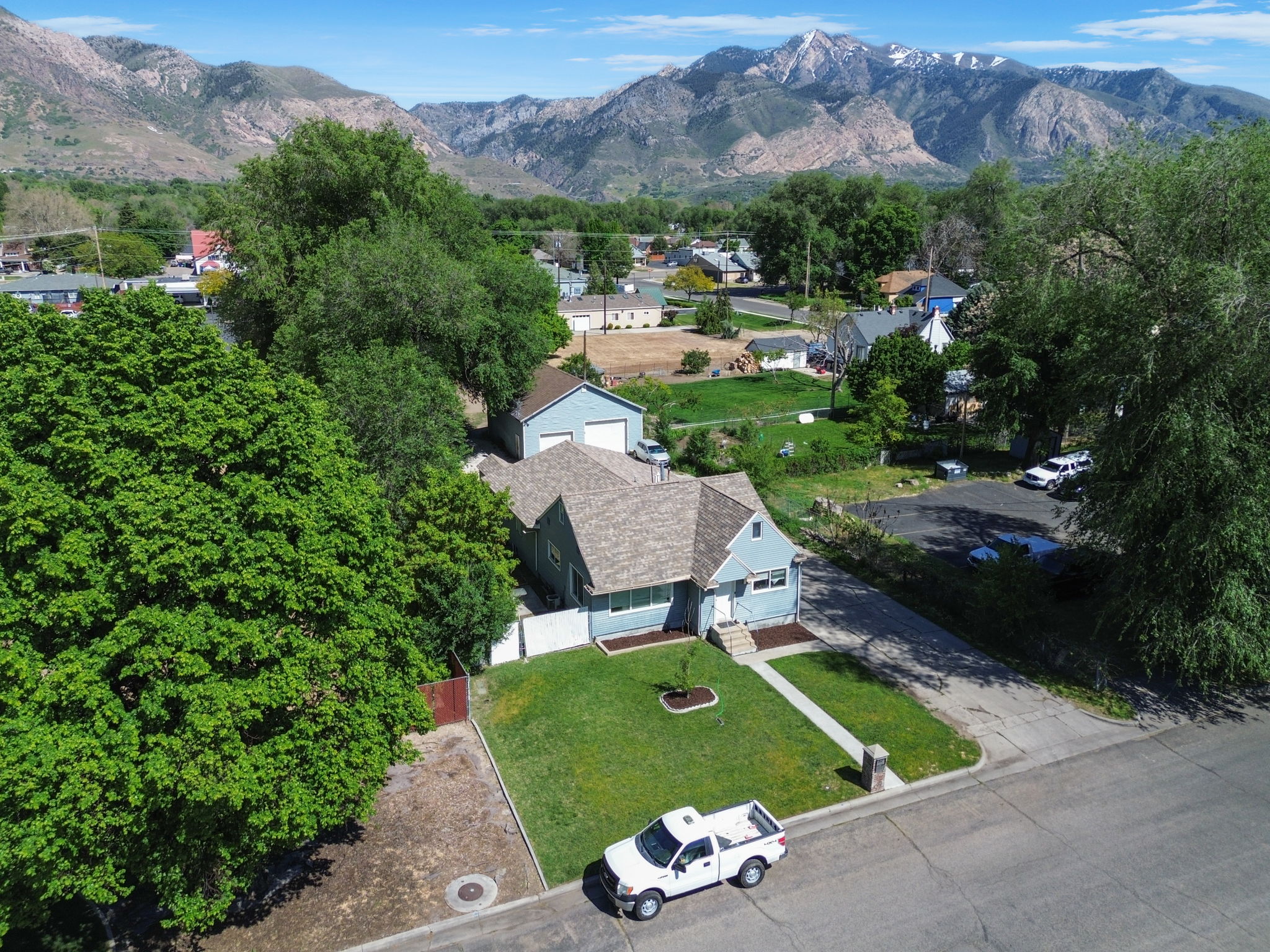 Light blue siding residence with a peaked roof, featuring a manicured front lawn and a visible attached garage