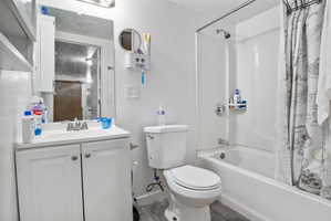 Bathroom featuring a white vanity with integrated sink, chrome faucet, wall-mounted mirror, and a full-sized bathtub with shower