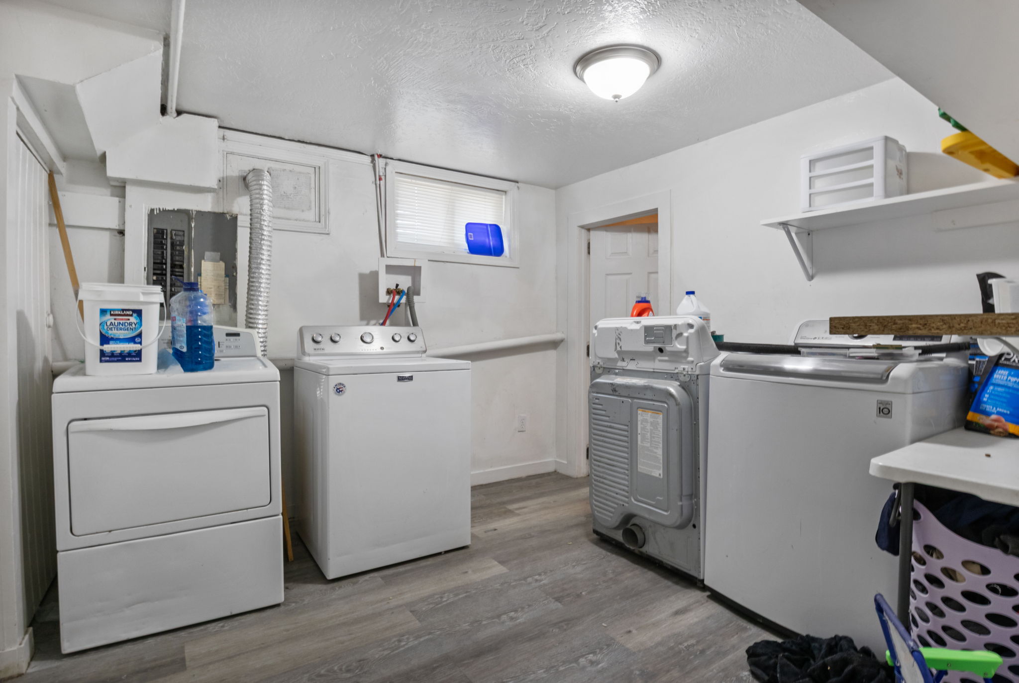 Dedicated laundry area featuring wood-finish flooring, white walls, and a ceiling-mounted light fixture