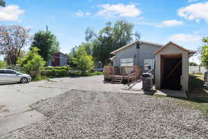 Rear exterior featuring a spacious wood deck with ramp access, gray horizontal siding, and a detached storage shed
