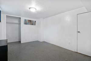 Spacious room featuring light-colored walls, a built-in closet with hanging rods, and an overhead flush-mount light fixture