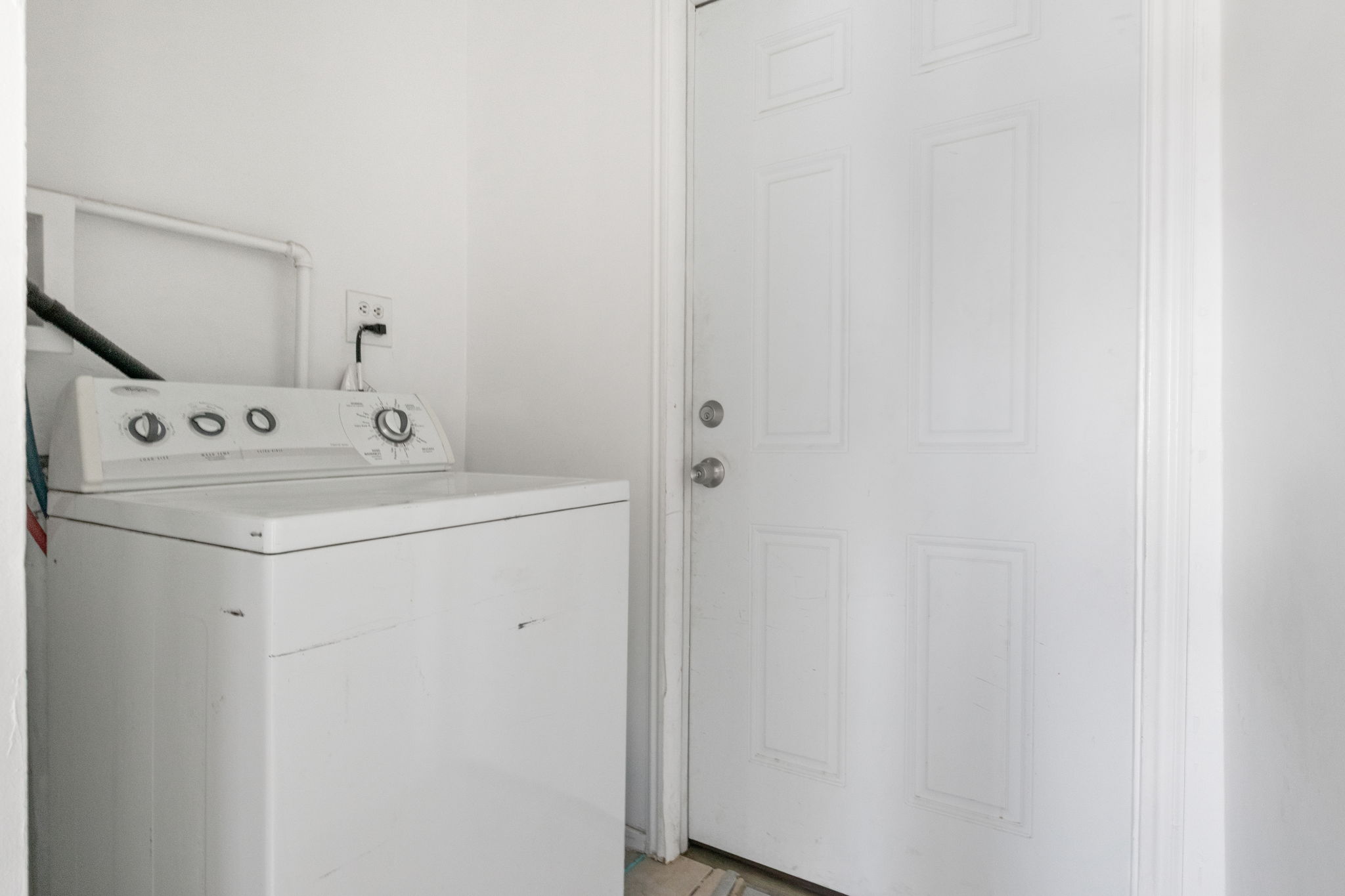Dedicated laundry area with white walls and a six-panel interior door