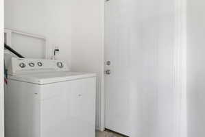 Dedicated laundry area with white walls and a six-panel interior door