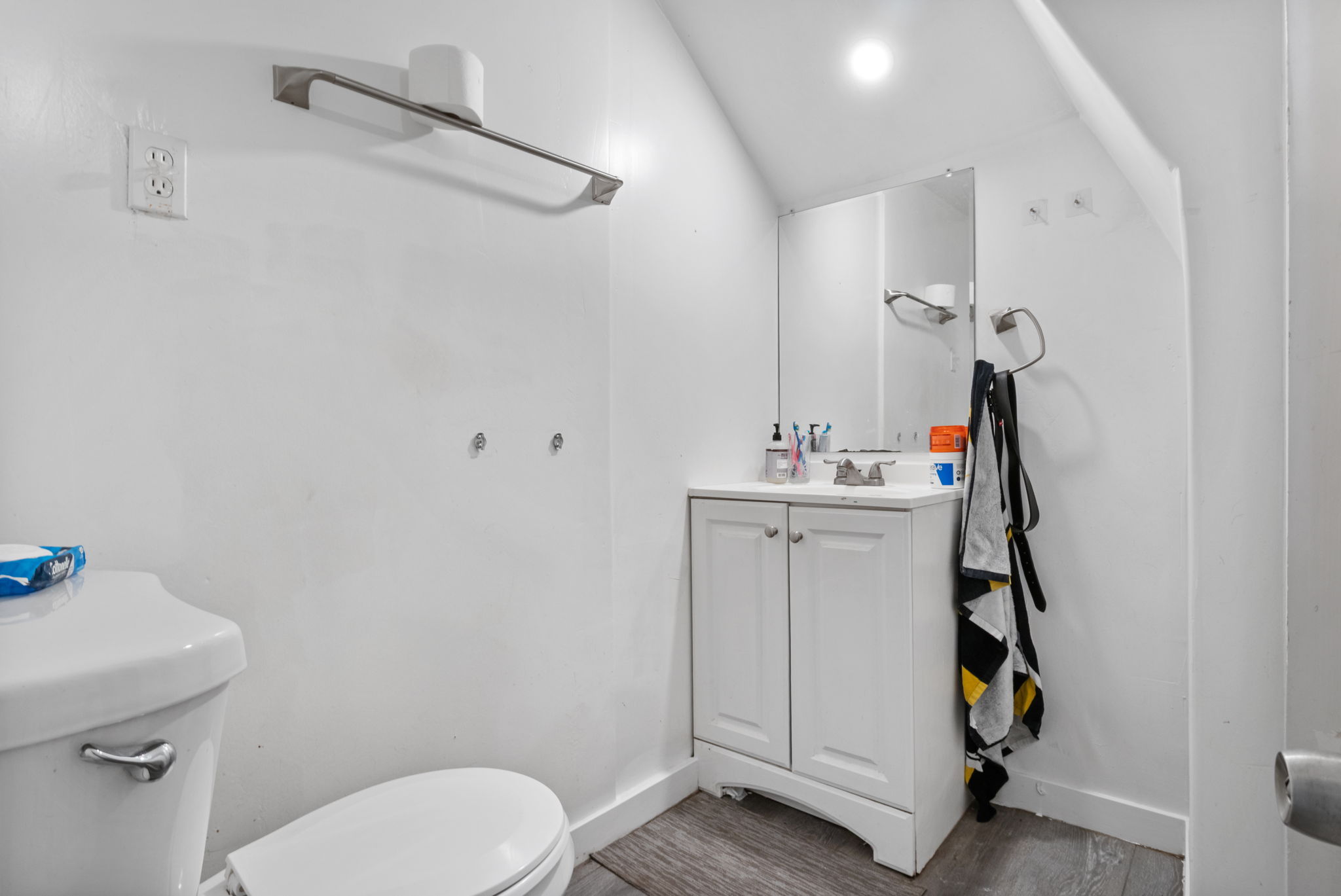 White vanity with dual cabinet storage, complemented by a wall-mounted mirror and overhead lighting