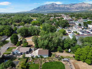 Aerial view of a residential property featuring a blue-sided home with a multi-pitched roof, a detached garage, and a large, undeveloped lot