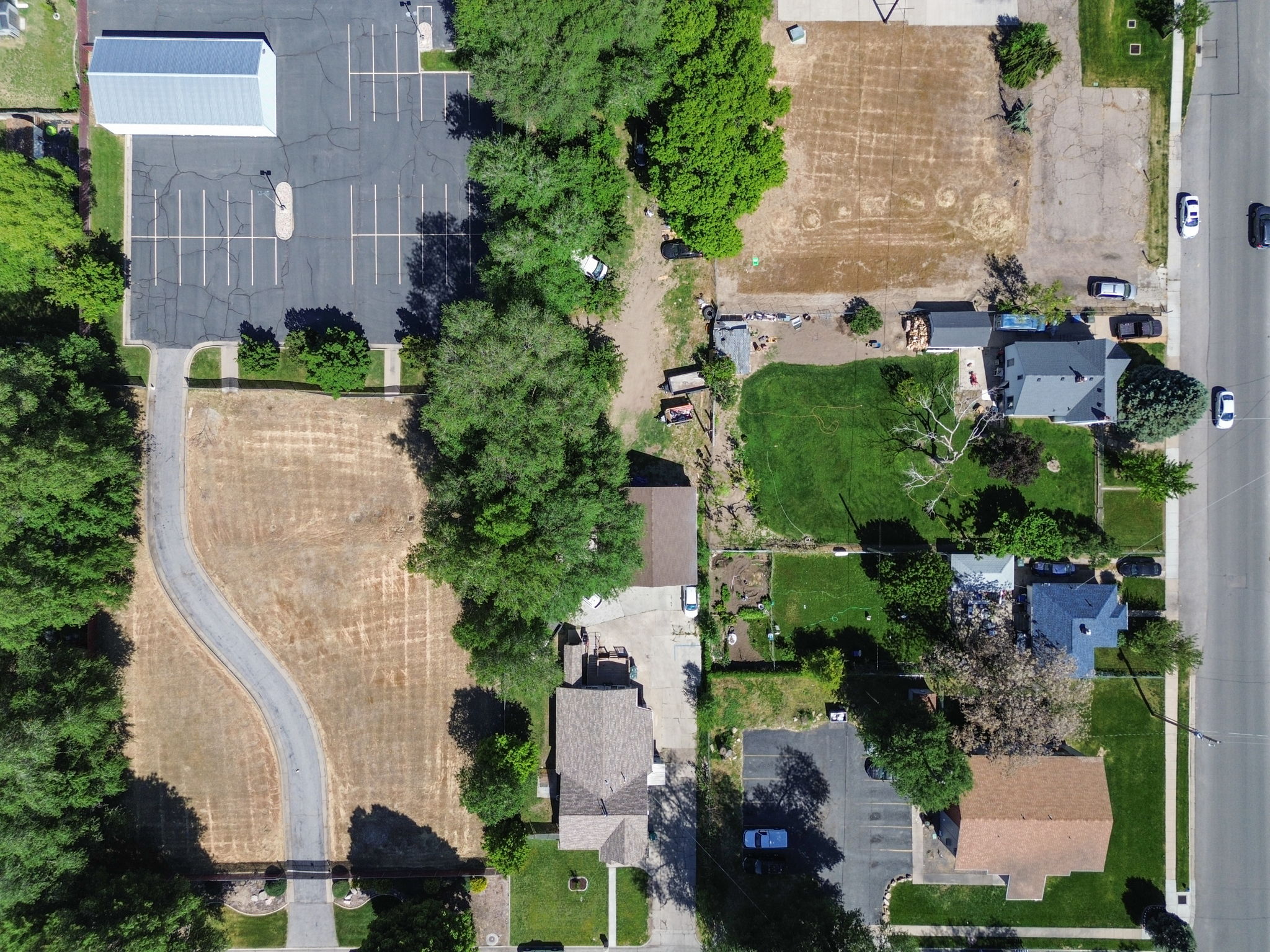 Aerial view showcasing a large, undeveloped lot with a winding paved driveway