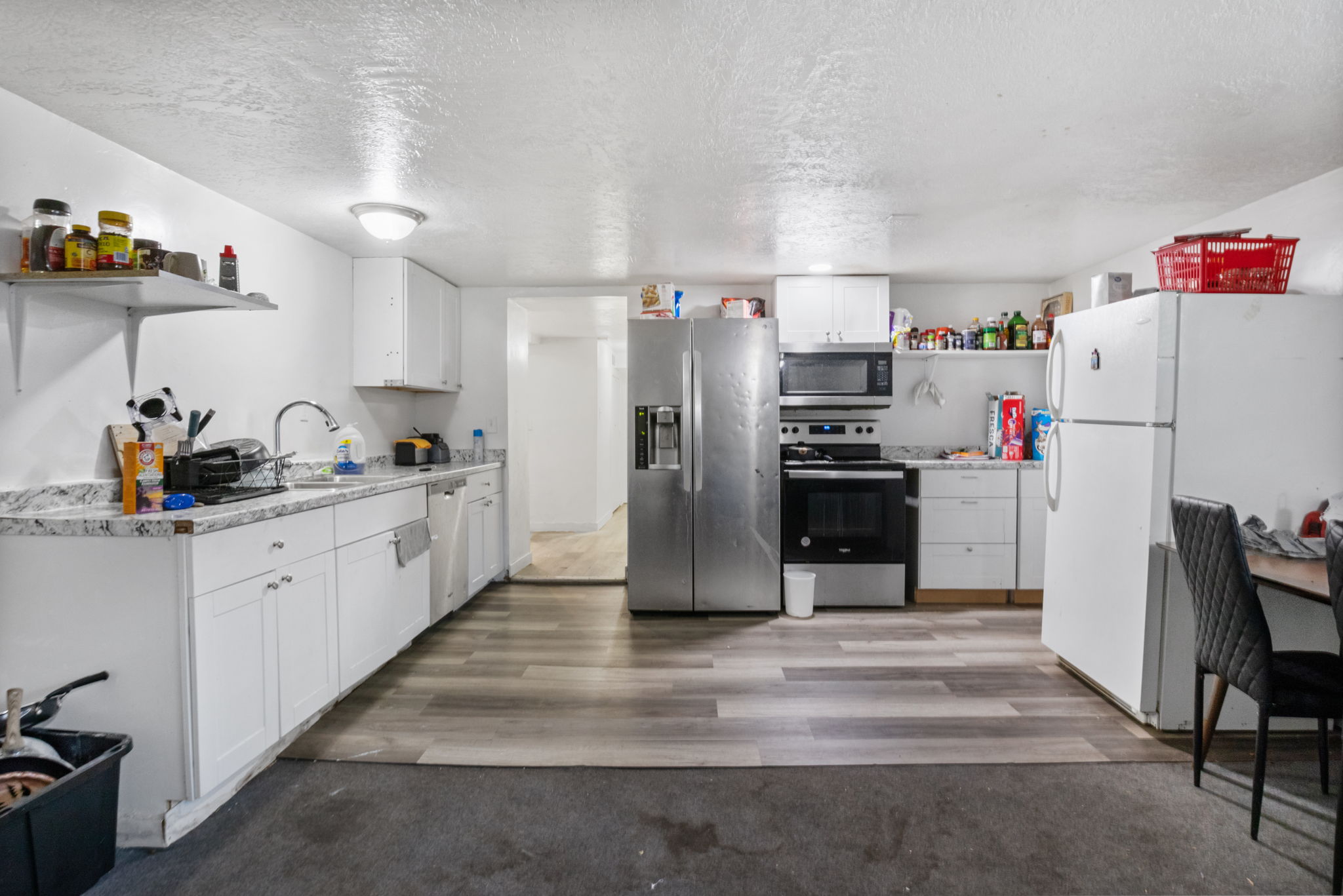 Kitchen featuring wood-finish flooring and white cabinetry