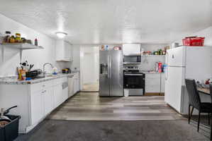 Kitchen featuring wood-finish flooring and white cabinetry