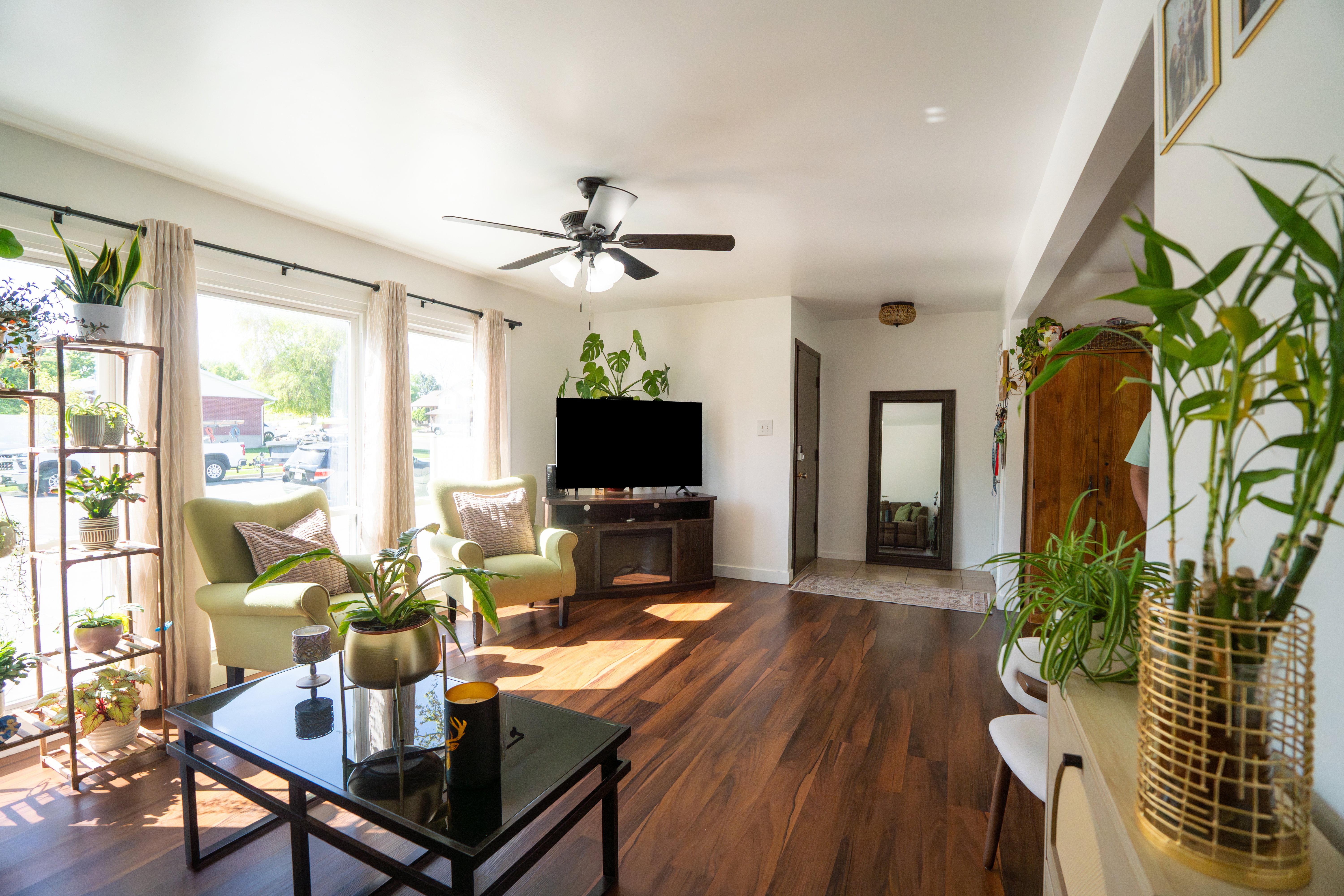 Living area featuring wood-finish flooring, a ceiling fan with integrated lighting, and multiple large windows