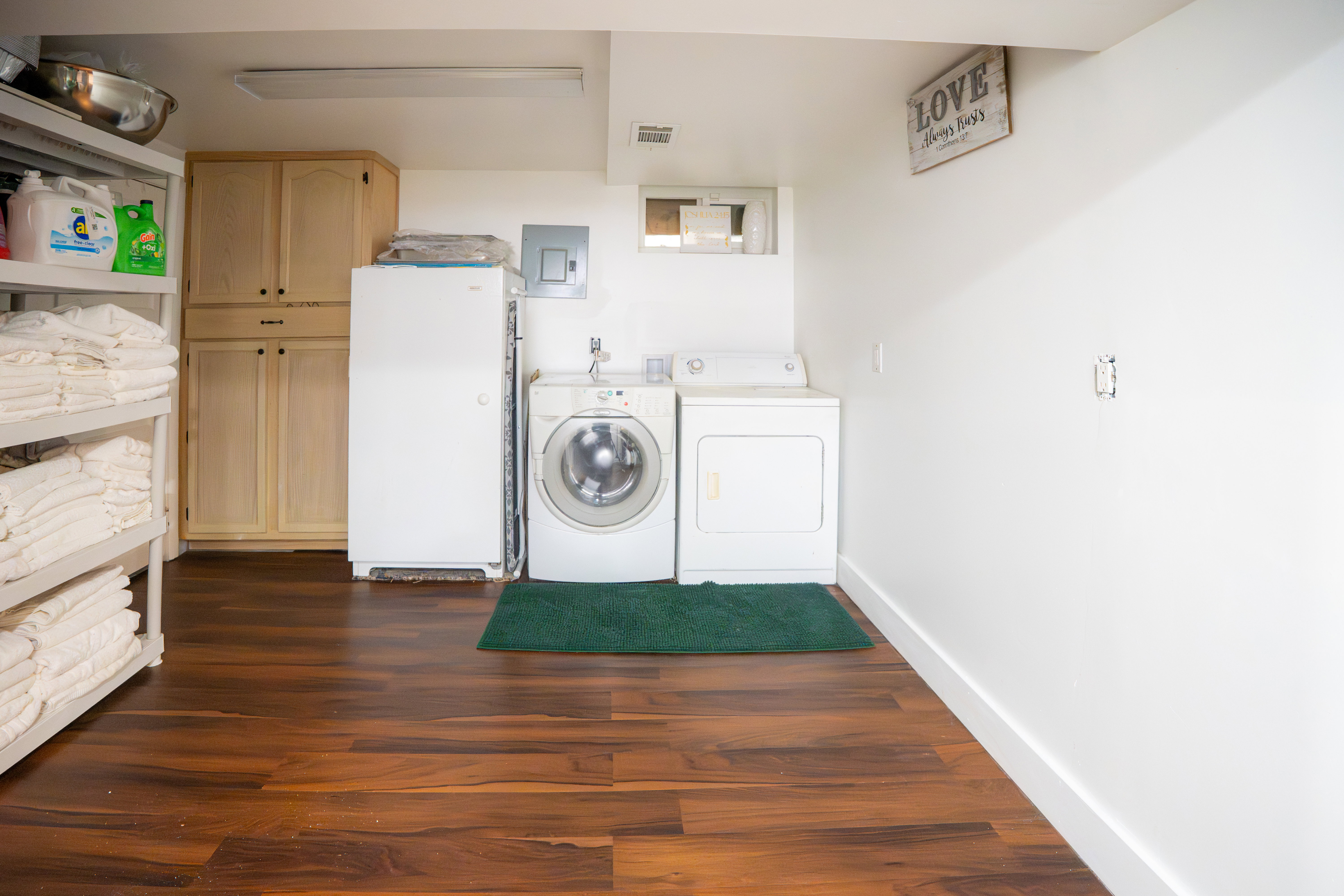 Laundry area featuring wood-finish flooring, white walls, and built-in cabinetry