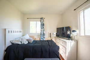 Bright room with white painted walls, wood-finish flooring, and two windows providing abundant natural light
