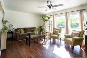 Bright living area featuring wood-finish flooring, white walls, and a ceiling fan with integrated lighting