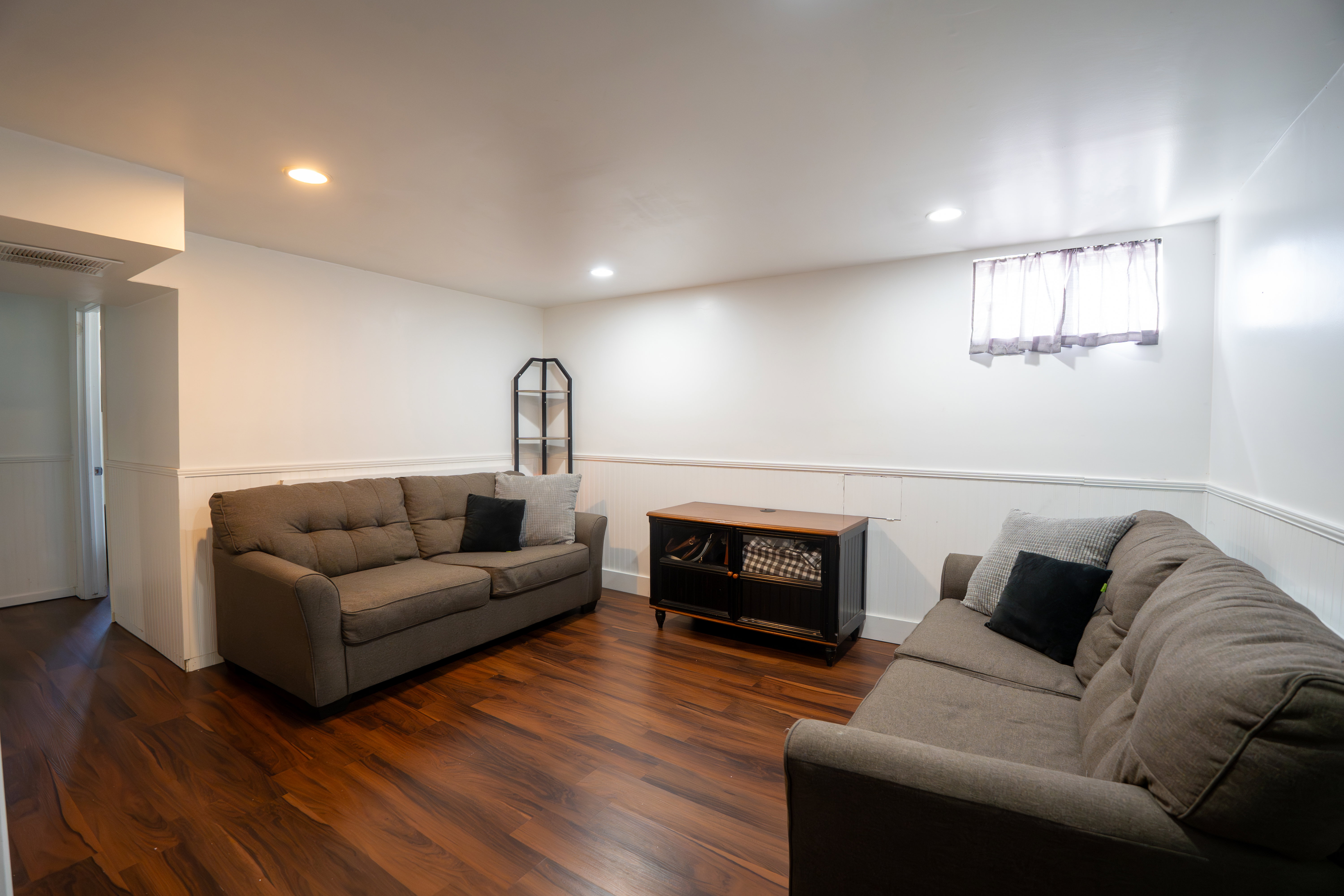 Spacious room featuring wood-finish flooring, recessed lighting, and white walls with wainscoting