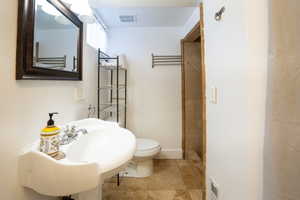 Pedestal sink with chrome fixtures, framed mirror, and tiled shower surround