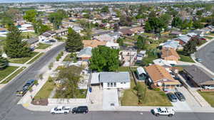 Corner lot property featuring a light-colored exterior, covered entry, and an established front yard with mature trees
