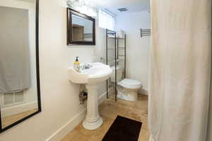 Pedestal sink with chrome fixtures, framed mirror, and warm-toned flooring