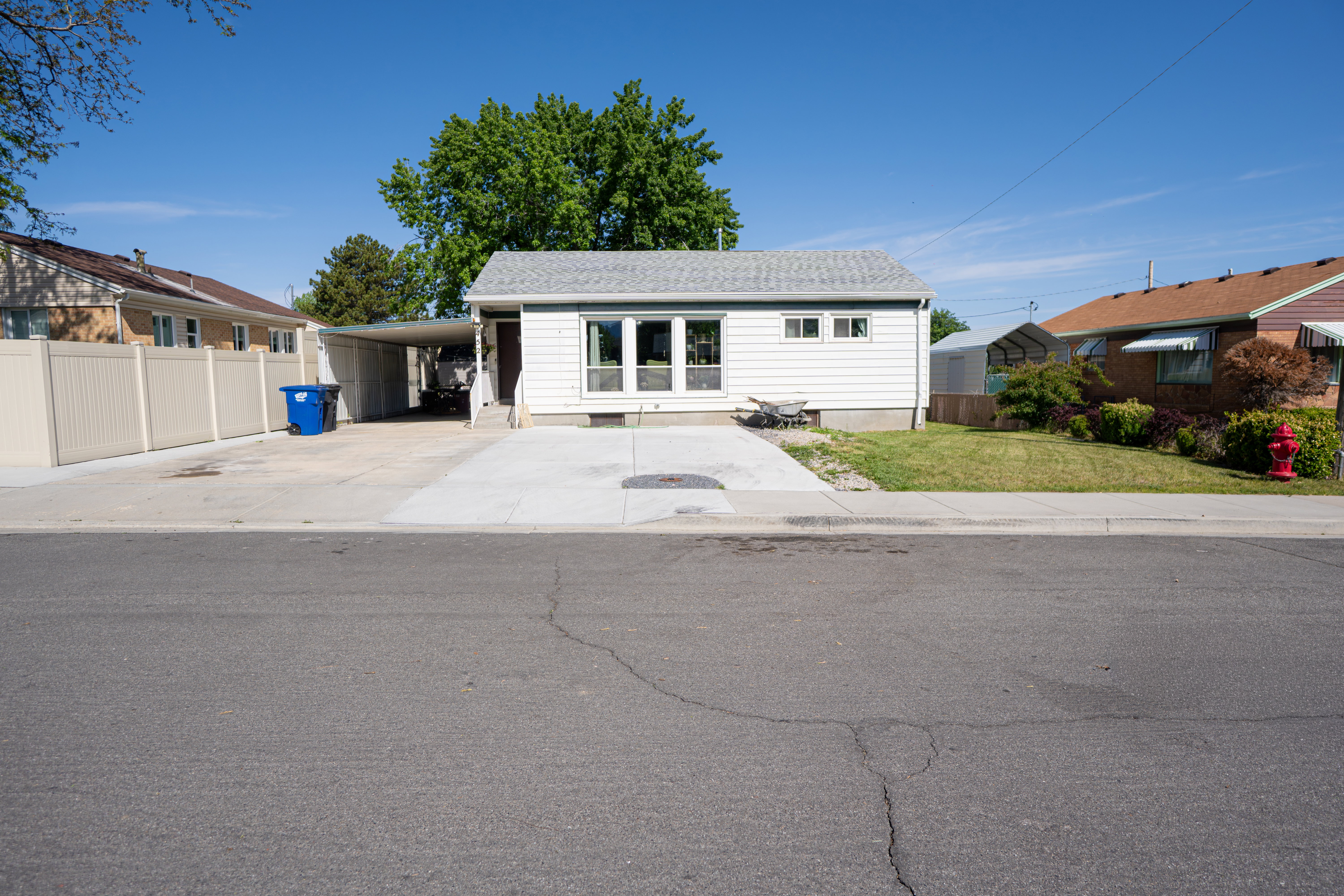 White-sided residence featuring a gray shingle roof, front-facing windows, and a concrete driveway