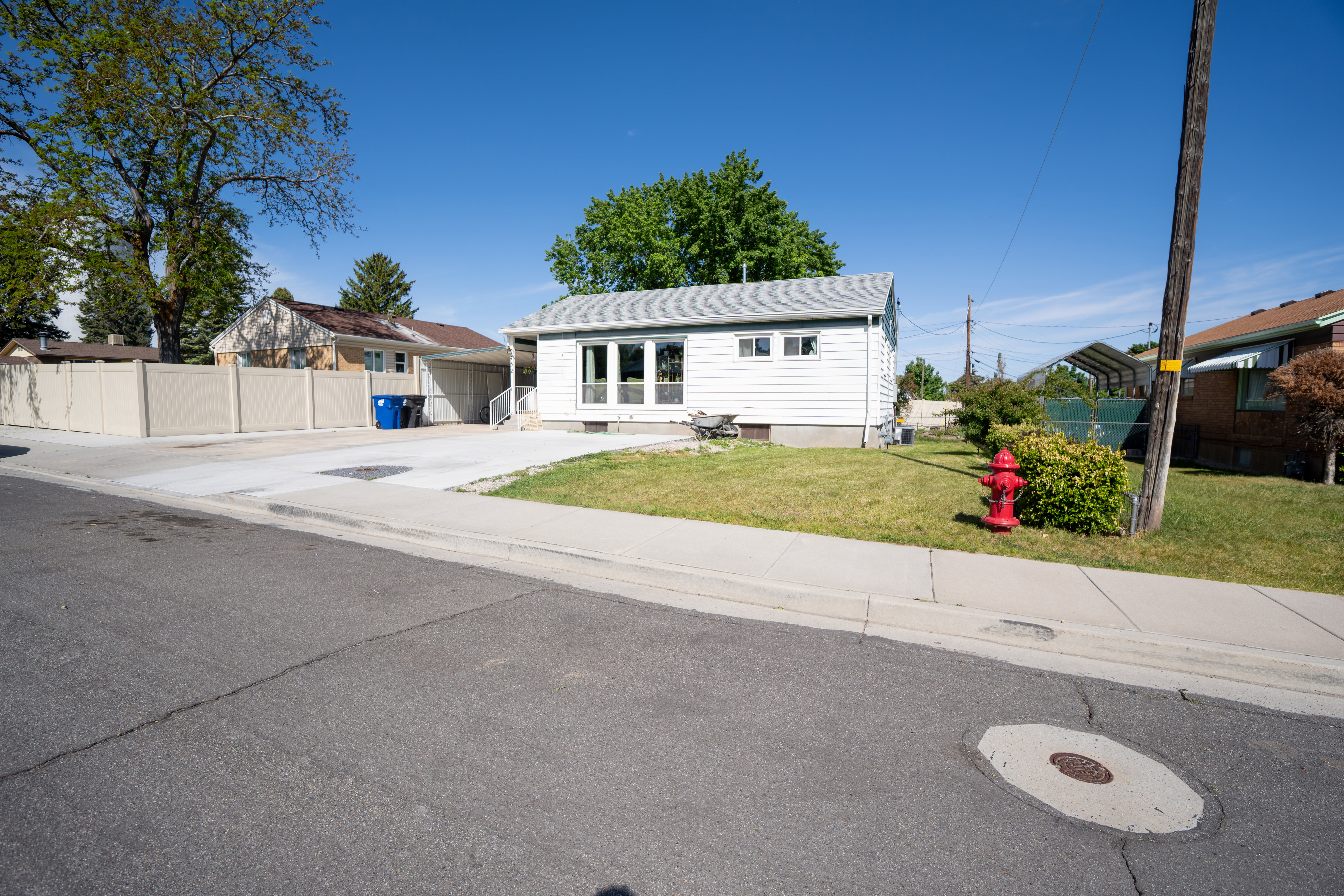 White siding exterior with a light gray roof, front lawn, and concrete driveway