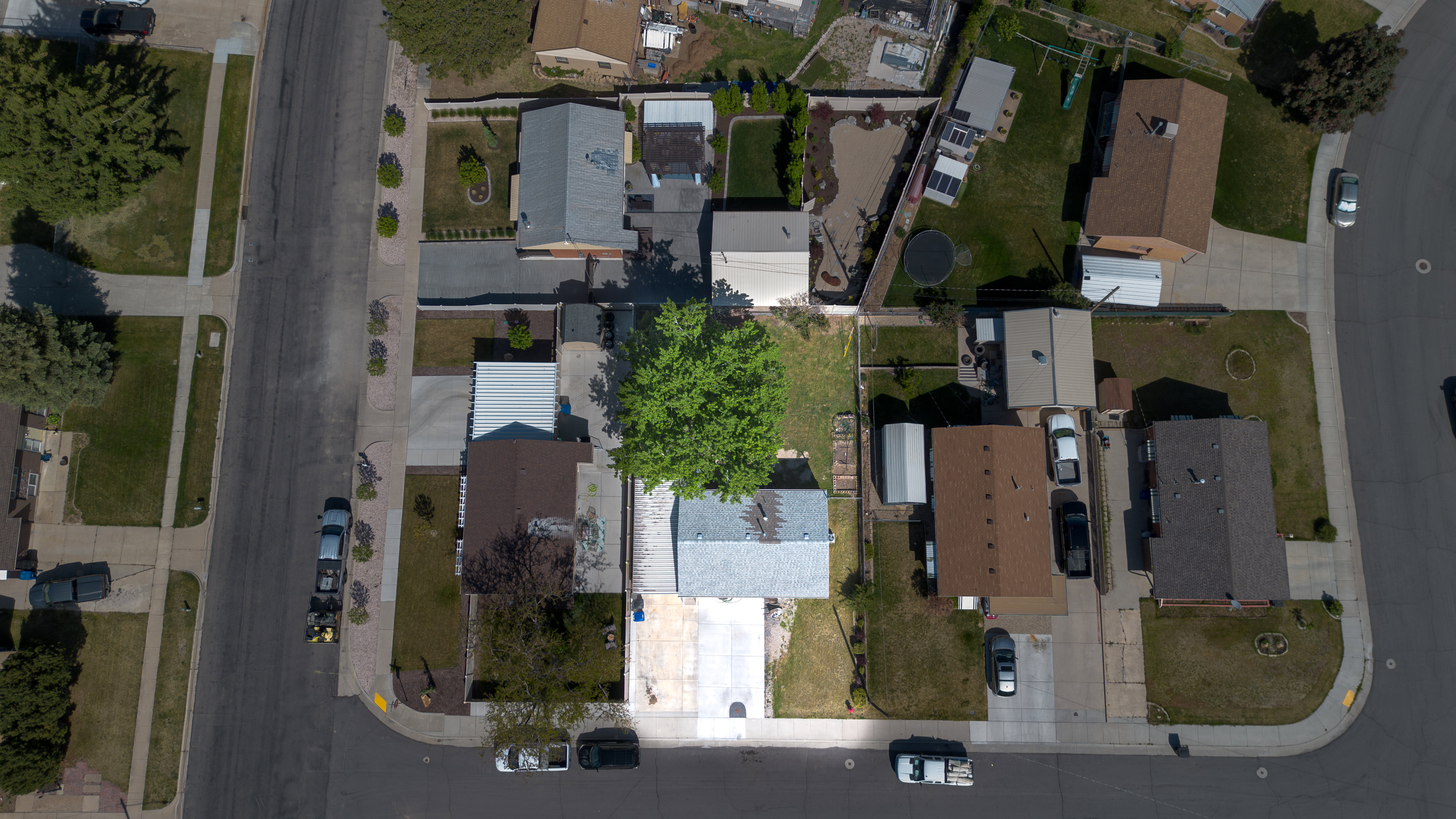 Aerial perspective showcasing a residential property with a detached garage, a mature shade tree, and a paved driveway