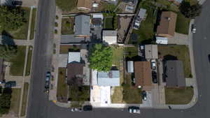 Aerial perspective showcasing a residential property with a detached garage, a mature shade tree, and a paved driveway