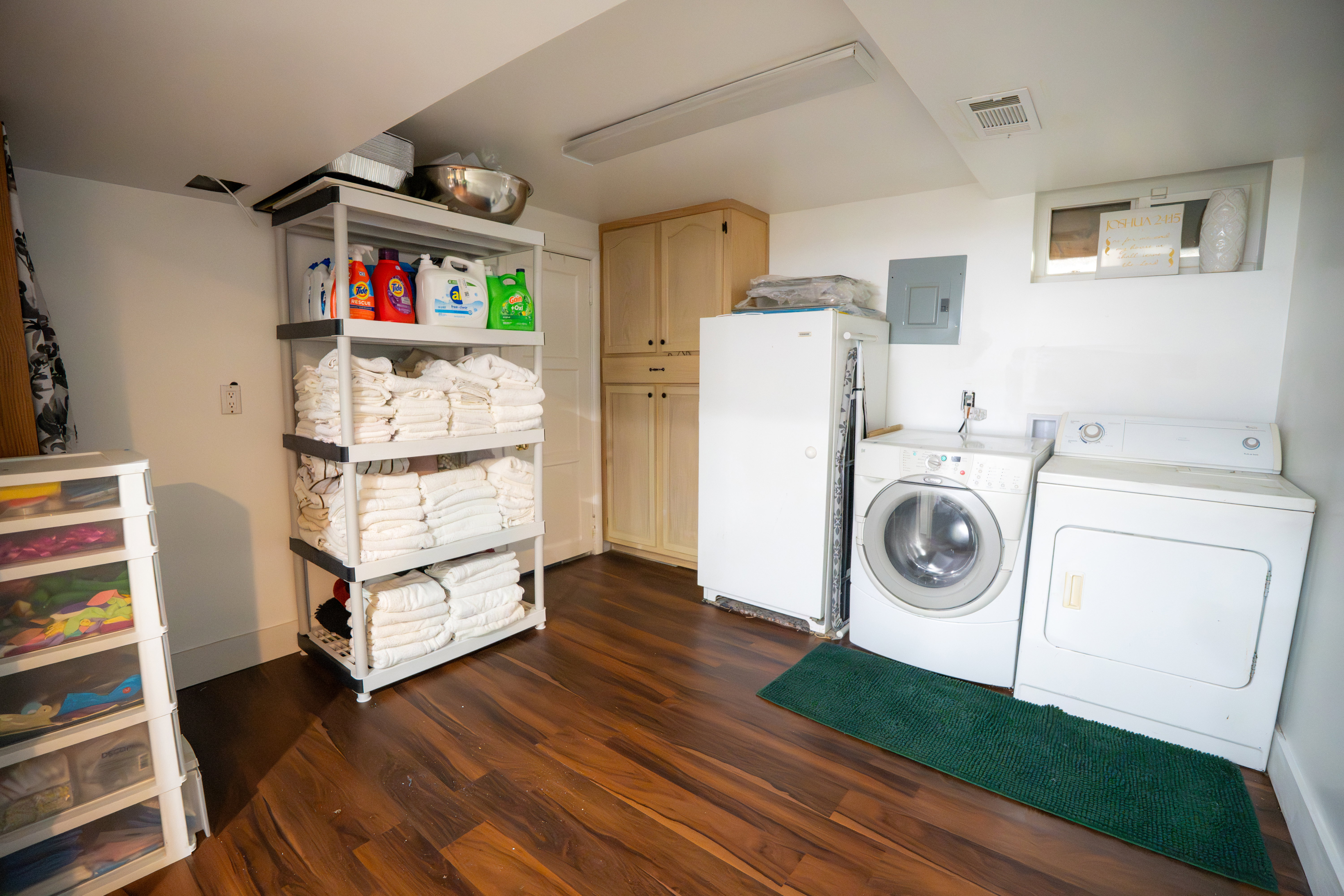 Wood-finish flooring throughout a utility space featuring built-in cabinetry, a window, and an overhead light fixture