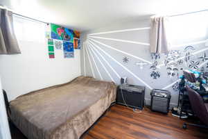 Room with wood-finish flooring, white walls, and a feature wall with a sunburst pattern