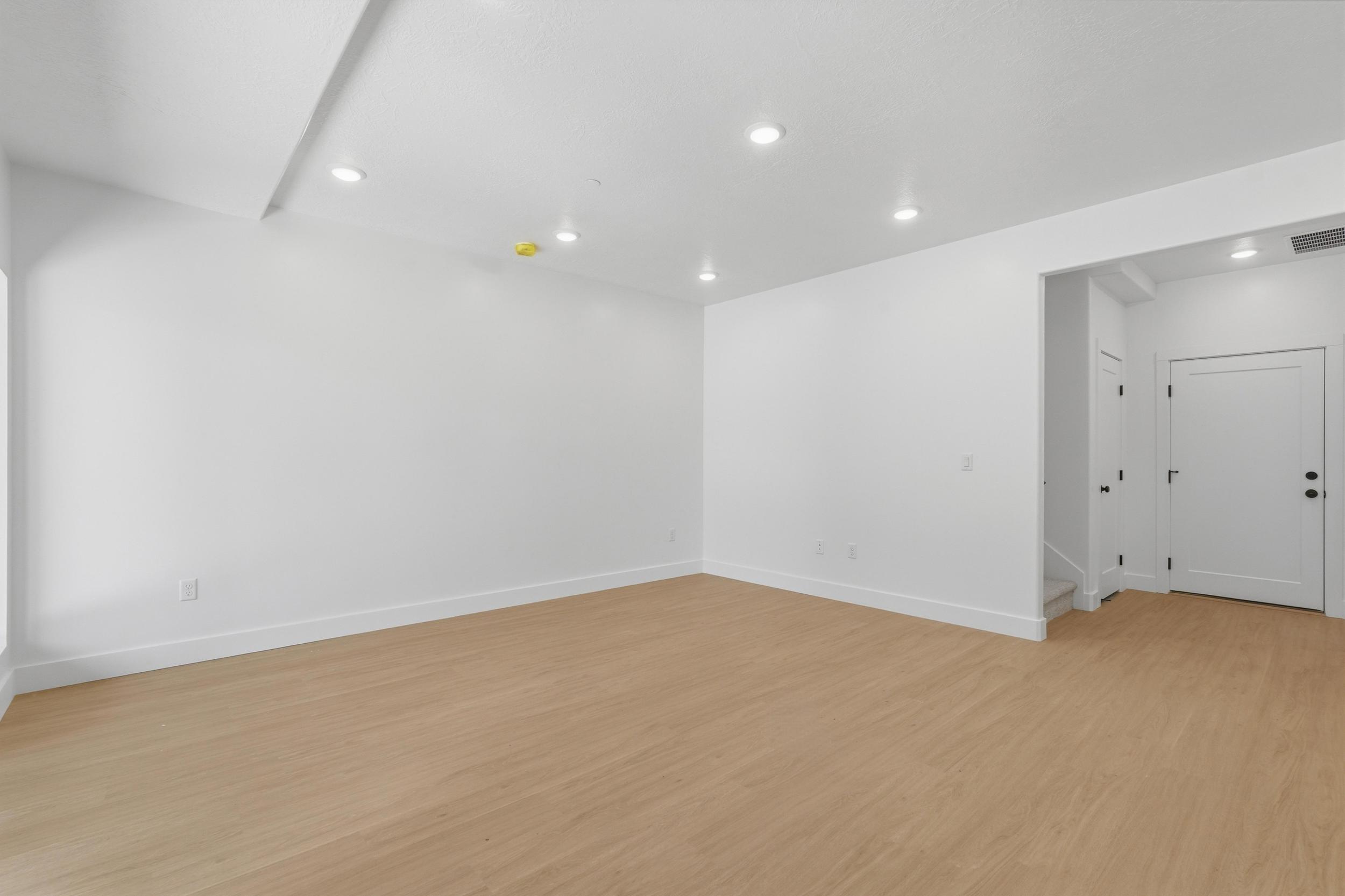 Spacious room featuring light wood-finish flooring, white walls, and recessed lighting