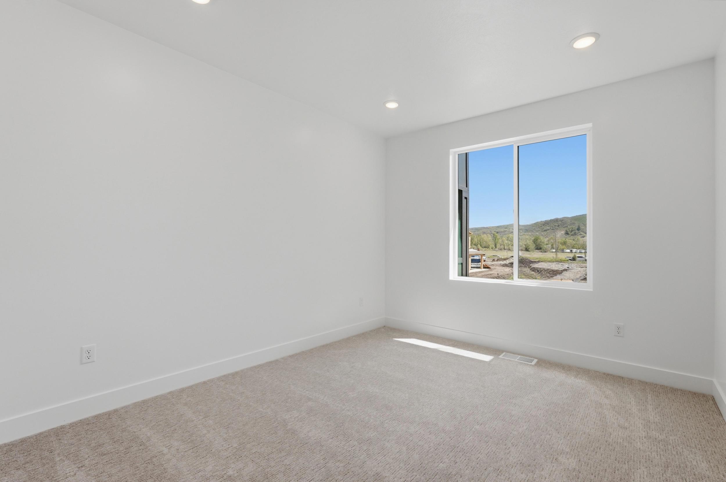 Bright room featuring recessed lighting, a large window, white baseboards, and neutral-toned carpeting