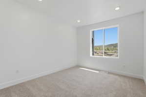 Bright room featuring recessed lighting, a large window, white baseboards, and neutral-toned carpeting