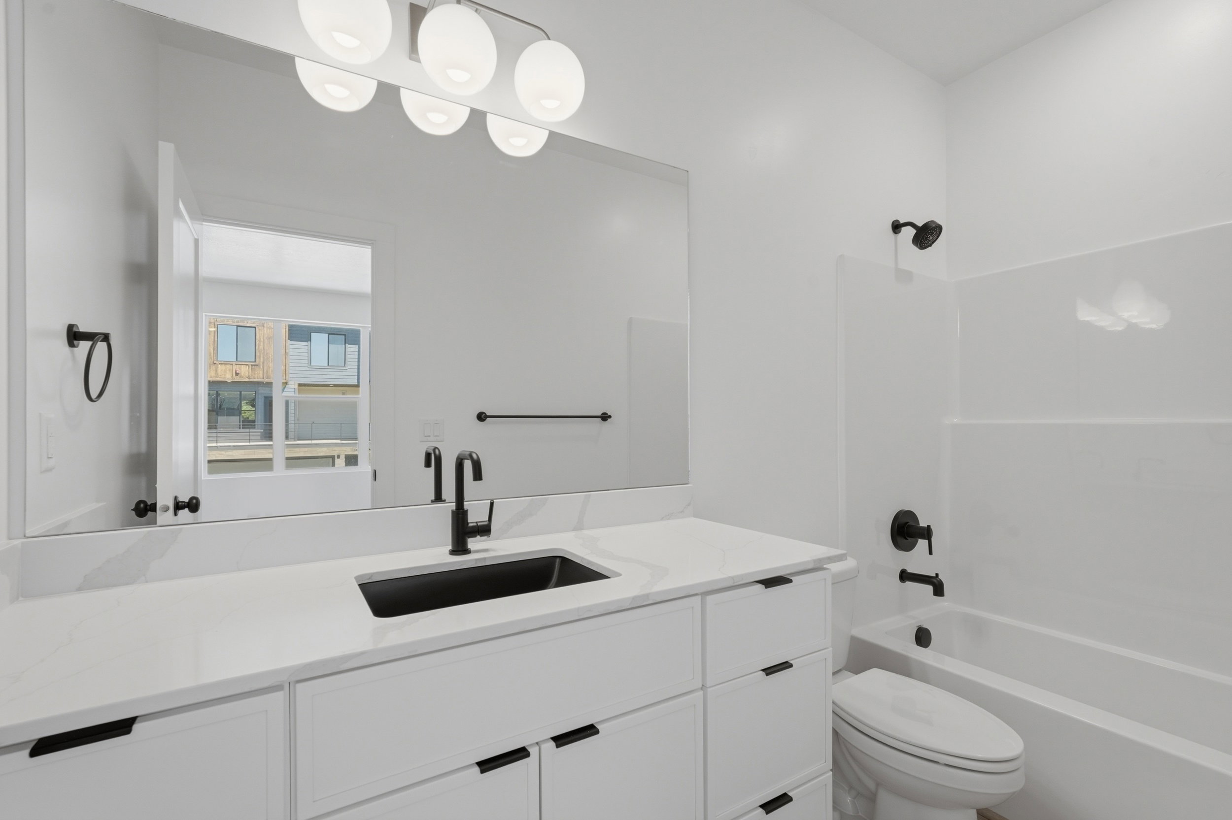 Bathroom featuring a large vanity with a white countertop and integrated sink, matte black faucet, and modern spherical light fixture