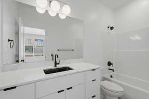 Bathroom featuring a large vanity with a white countertop and integrated sink, matte black faucet, and modern spherical light fixture