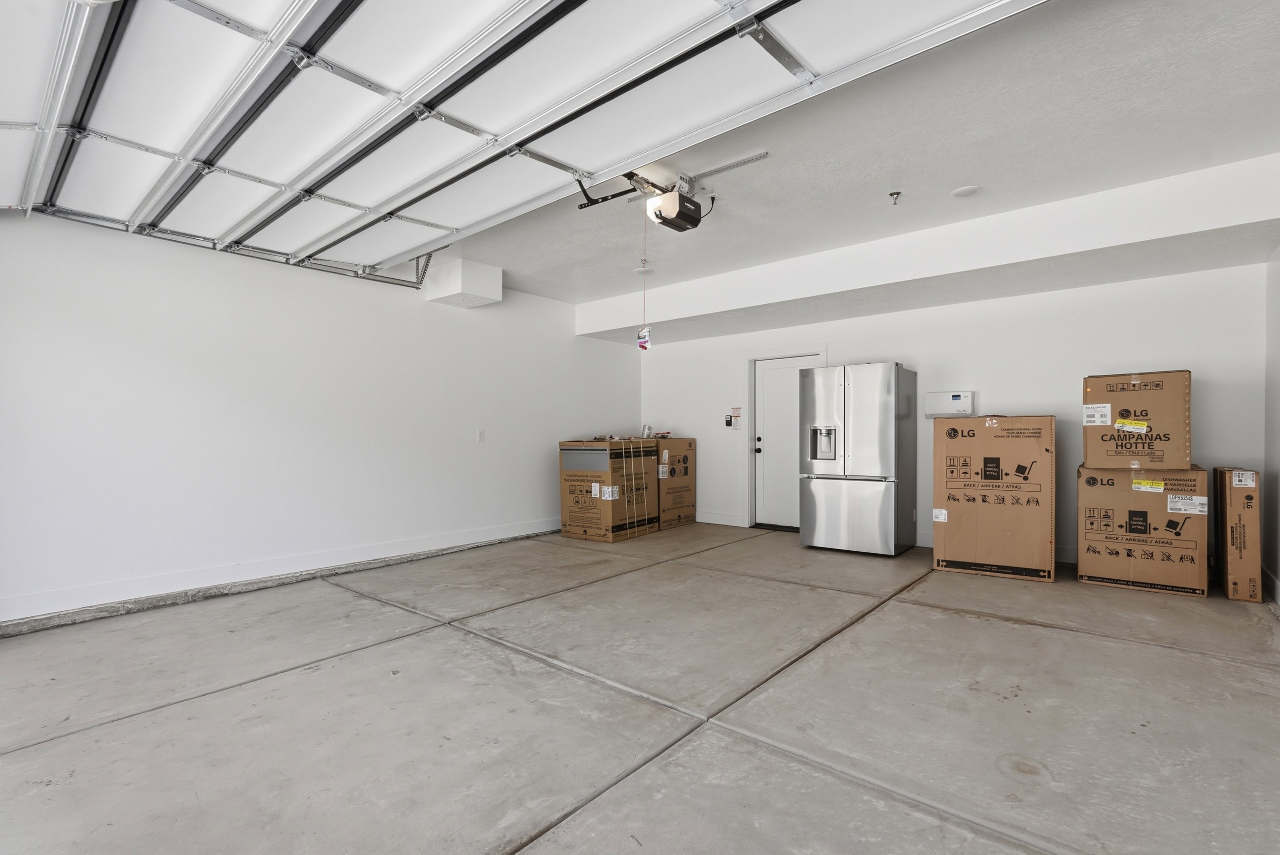 Spacious garage with a concrete floor, white walls, and an overhead garage door opener mechanism