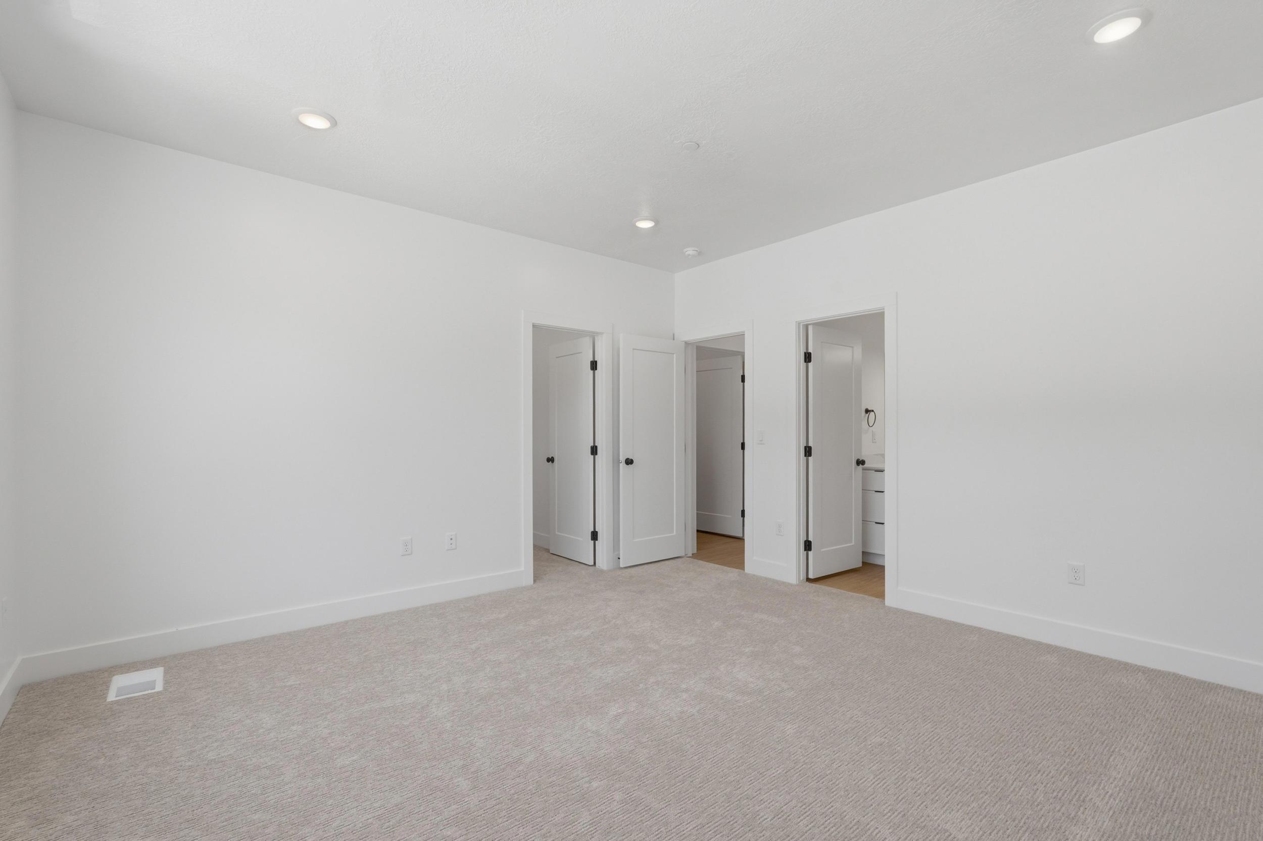Neutral wall finishes, recessed ceiling lighting, light-toned carpet, and multiple interior doors