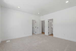 Neutral wall finishes, recessed ceiling lighting, light-toned carpet, and multiple interior doors