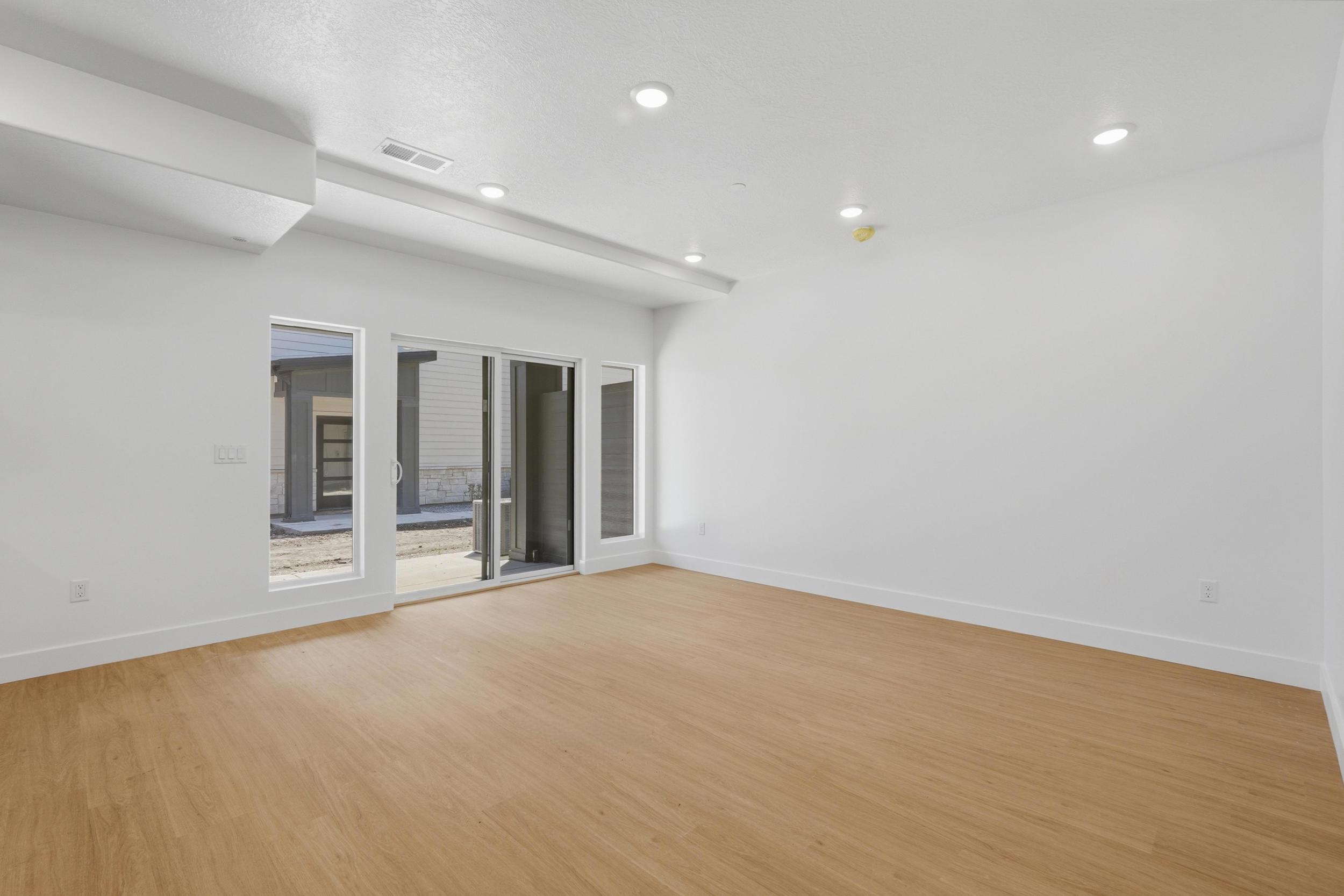 Spacious Living room featuring light wood-finish flooring, white walls, and recessed lighting