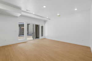 Spacious Living room featuring light wood-finish flooring, white walls, and recessed lighting