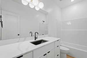 Contemporary bathroom vanity featuring a wide mirror, white countertop, and dark-finish fixtures