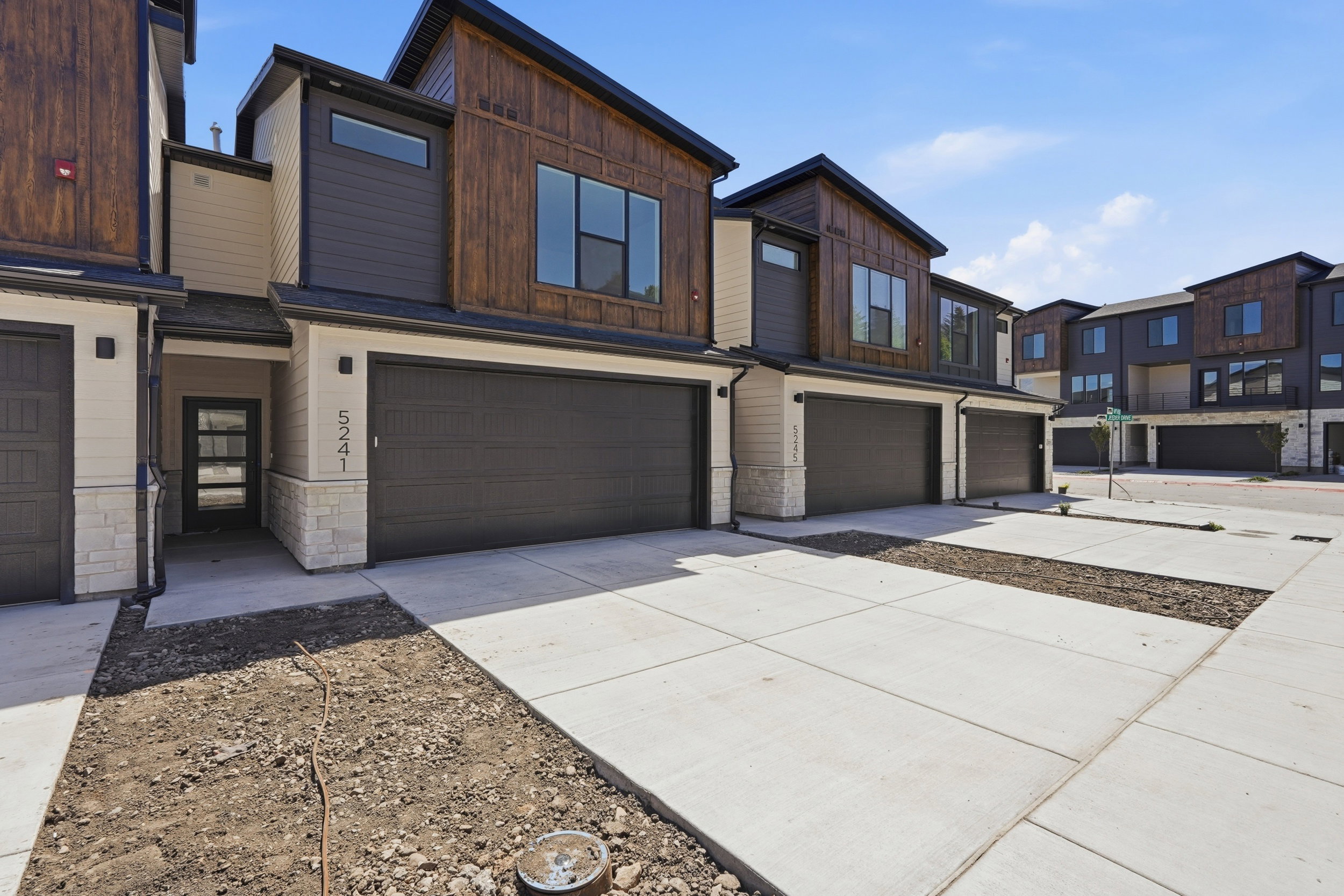 Contemporary townhome exterior featuring a combination of horizontal siding, wood-finish paneling, and stone accents