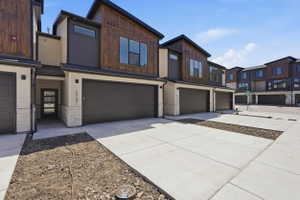 Contemporary townhome exterior featuring a combination of horizontal siding, wood-finish paneling, and stone accents