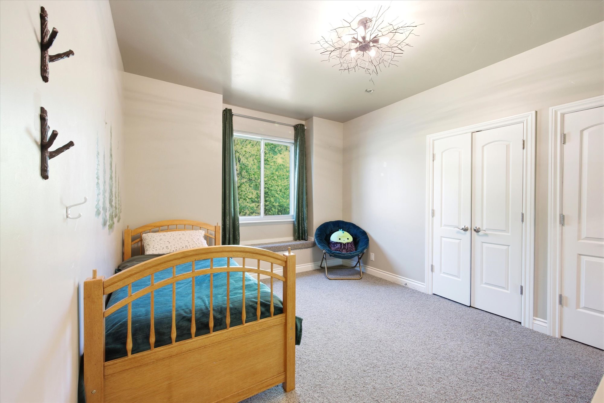 Light-filled room featuring a large window, neutral carpeting, and a decorative ceiling fixture