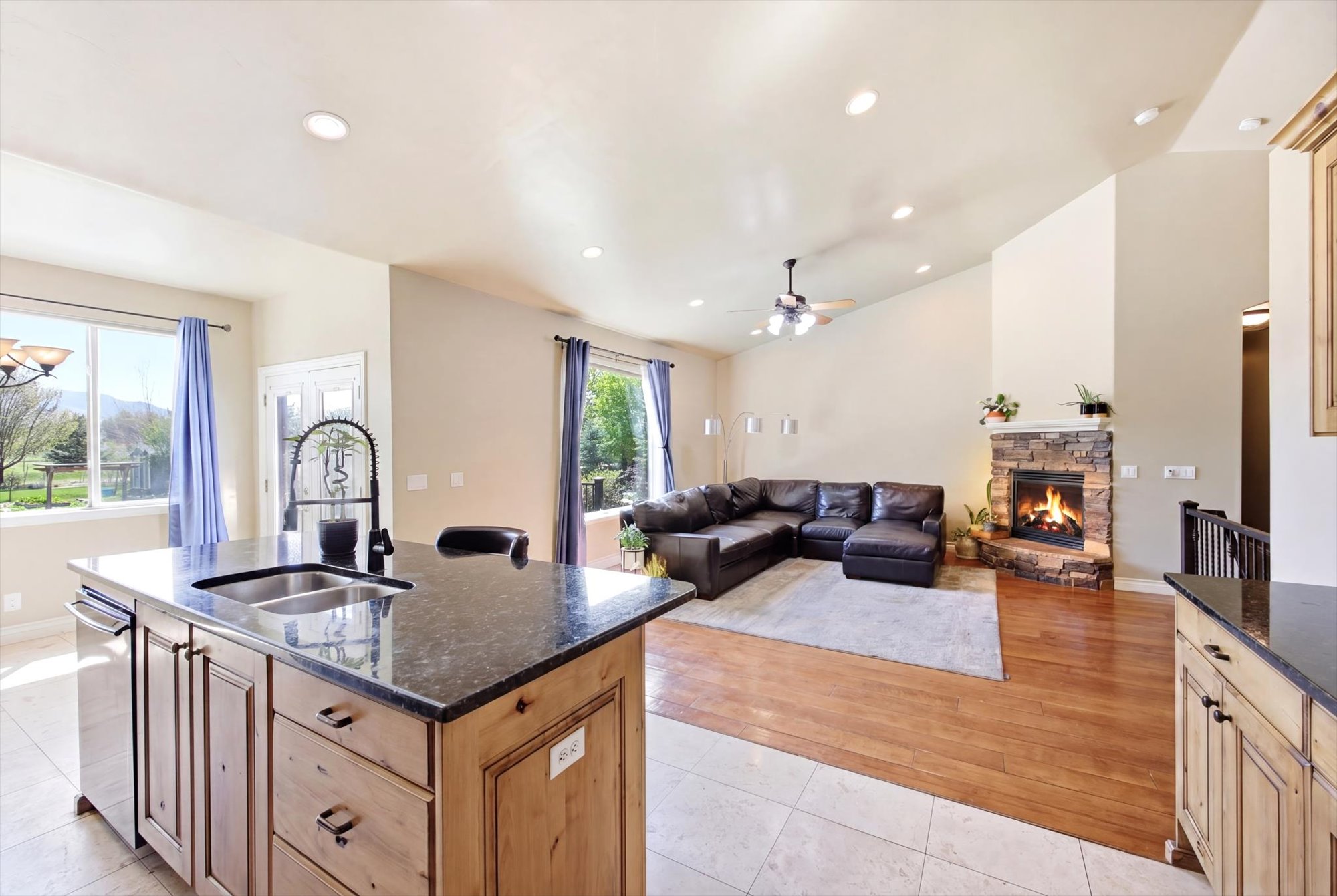 Kitchen island with dark countertop, undermount double sink, and stainless steel dishwasher