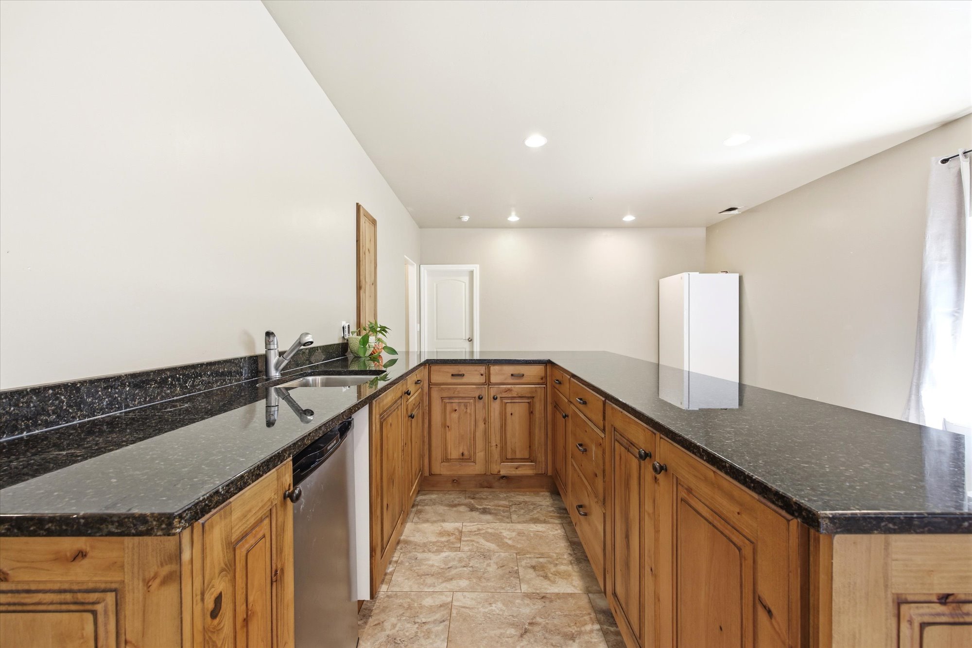 Expansive U-shaped counter space featuring dark stone countertops and natural wood cabinetry